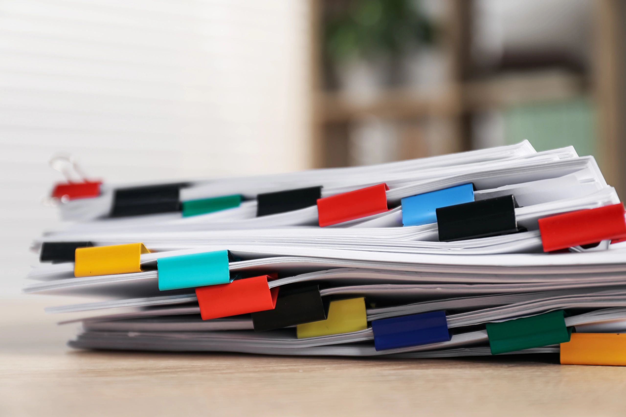 Stack of documents with binder clips on wooden table